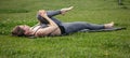 Young beautiful woman doing yoga exercise in green park near the pond. Exercices for improve the flexibility. Wellbeing