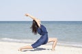 Young beautiful woman doing yoga at seaside in blue dress Royalty Free Stock Photo