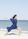 Young beautiful woman doing yoga at seaside in blue dress Royalty Free Stock Photo