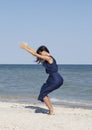 Young beautiful woman doing yoga at seaside in blue dress Royalty Free Stock Photo