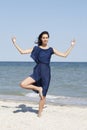 Young beautiful woman doing yoga at seaside in blue dress Royalty Free Stock Photo