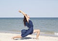 Young beautiful woman doing yoga at seaside in blue dress Royalty Free Stock Photo