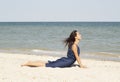 Young beautiful woman doing yoga at seaside in blue dress Royalty Free Stock Photo