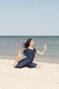 Young beautiful woman doing yoga at seaside in blue dress Royalty Free Stock Photo