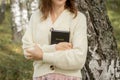 A young beautiful woman in a dress and hat stands and reads a Bible Royalty Free Stock Photo