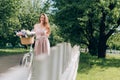 young beautiful woman in dress with retro bicycle with wicker basket full of flowers