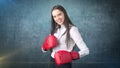 Young beautiful woman dress in white shirt standing in combat pose with red boxing gloves. Business concept. Royalty Free Stock Photo