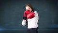 Young beautiful woman dress in white shirt standing in combat pose with red boxing gloves. Business concept. Royalty Free Stock Photo