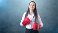 Young beautiful woman dress in white shirt standing in combat pose with red boxing gloves. Business concept. Royalty Free Stock Photo