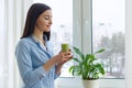 Young beautiful woman with drink green blended smoothie kiwi