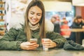 Young beautiful woman drinking a coffee in a cafe bar while typing on mobile smart phone using application chat Royalty Free Stock Photo