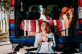 young beautiful woman drinking coffee or tea camping outdoors with a van and her two dogs. Travel concept