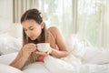 Young beautiful woman drinking a Cup of coffee in bed Royalty Free Stock Photo
