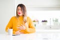 Young beautiful woman drinking a cup of coffee at home with hand on stomach because indigestion, painful illness feeling unwell