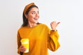 Young beautiful woman drinking glass of take away coffee over isolated white background pointing and showing with thumb up to the Royalty Free Stock Photo