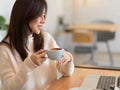 Beautiful woman drinking morning coffee while working on laptop computer at cafe bar Royalty Free Stock Photo