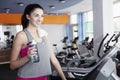 Young beautiful woman drinks water on the treadmill in the gym Royalty Free Stock Photo