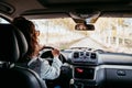 young beautiful woman driving a van by a path of trees. travel concept, view from inside