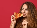 Young beautiful woman eat slice of pepperoni pizza with closed eyes smiling on red pink