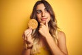 Young beautiful woman eating biscuit over grey isolated background serious face thinking about question, very confused idea