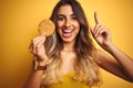 Young beautiful woman eating biscuit over grey isolated background surprised with an idea or question pointing finger with happy Royalty Free Stock Photo