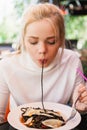 Young beautiful woman eating black pasta with seafood and cuttlefish ink in the outdoor restaurant. Funny and beautiful. Royalty Free Stock Photo