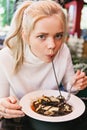 Young beautiful woman eating black pasta with seafood and cuttlefish ink in the outdoor restaurant. Funny and beautiful. Royalty Free Stock Photo