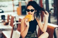 Young beautiful woman eating burger and enjoying while sitting outdoor. Fastfood Unhealthy Lifestyle Fashion Food concepts Royalty Free Stock Photo