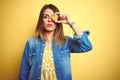 Young beautiful woman eating chocolate chips cookie over yellow background with a confident expression on smart face thinking