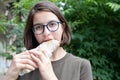 Young beautiful woman eating fast food while walking in the park, close-up. Unhealthy food concept, fast food Royalty Free Stock Photo