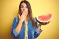 Young beautiful woman eating fresh healthy watermelon slice over yellow background cover mouth with hand shocked with shame for Royalty Free Stock Photo