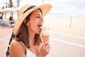 Young beautiful woman eating ice cream cone by the beach on a sunny day of summer on holidays Royalty Free Stock Photo