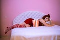 Girl watching  movie with snack in a paper striped glass on a light bed Royalty Free Stock Photo