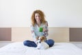 Young beautiful woman enjoying a healthy green detox juice on bed. Cute small dog besides. Lifestyle, indoors Royalty Free Stock Photo