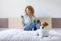 Young beautiful woman enjoying a healthy green detox juice on bed. Cute small dog besides. Lifestyle, indoors Royalty Free Stock Photo