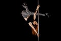 Young and beautiful woman exercises pole dance against a black background Royalty Free Stock Photo