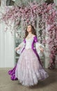 Young beautiful woman in fantasy rococo style medieval dress dancing looking up near door with pink flowers Royalty Free Stock Photo