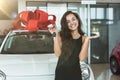 Young beautiful woman feels happy holding keys from her brand new car standing in dealership center Royalty Free Stock Photo