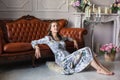 Young beautiful woman in floral dress sits on floor Royalty Free Stock Photo