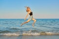 Young beautiful woman flying over the sea, happy female jumping over water