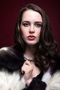 Young beautiful woman in fur coat and with green pistachio colour eyes on red marsala background Royalty Free Stock Photo