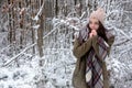 Young beautiful woman, girl portrait with shawl, hat.squeezes her hands from cold frost in winter forest Royalty Free Stock Photo