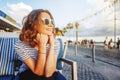 young beautiful woman girl in a striped T-shirt sitting in a street cafe smiling, seaside town, vacation and travel Royalty Free Stock Photo