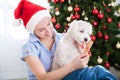 Young beautiful woman gives present bone to her dog for christma