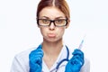 Young beautiful woman in glasses and in medical clothes holds a syringe on white isolated background, emotions, doctor, medicine Royalty Free Stock Photo