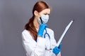 Young beautiful woman on a gray background with glasses holds a folder with documents and pen, doctor, medicine Royalty Free Stock Photo