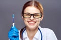 Young beautiful woman on a gray background with glasses holds a syringe, medicine, doctor Royalty Free Stock Photo