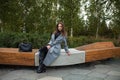 Young beautiful woman in a gray coat sitting on a bench in the autumn park Royalty Free Stock Photo