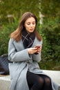 Young beautiful woman in a gray coat writes a message Royalty Free Stock Photo