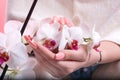 Young Beautiful Woman with Pink Spring Manicure Holding White Orchid Flower